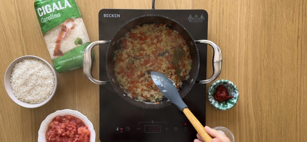 Num tacho com azeite, refogue a cebola, os alhos e o pimento