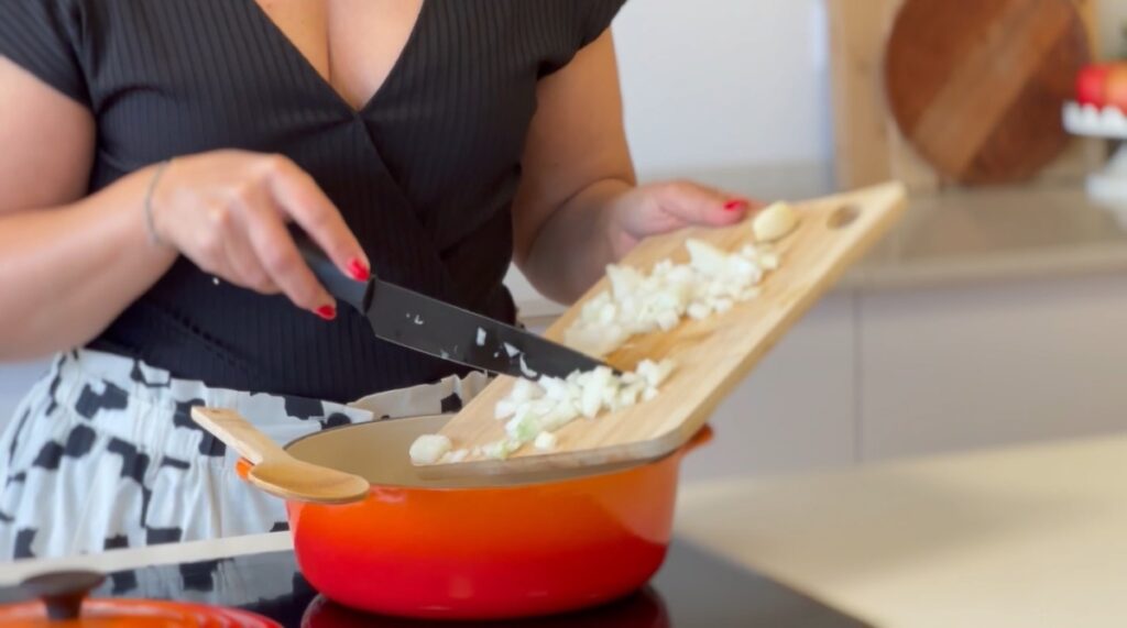 O refogado é a base deste prato. Comece por picar a cebola e os alhos, coloque no tacho e acrescente o azeite.