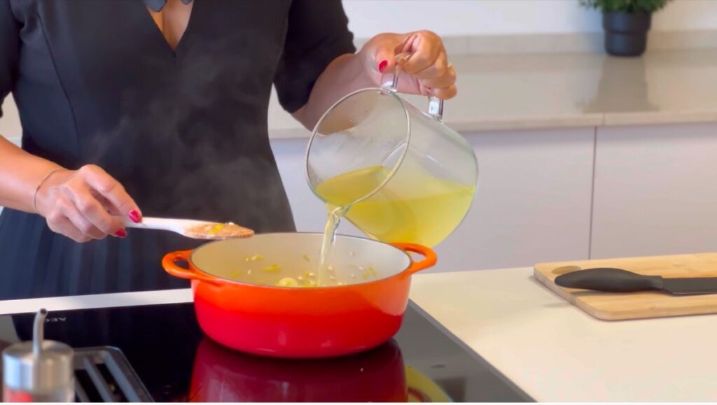 adicione o caldo de legumes a ferver aos poucos, uma concha de cada vez