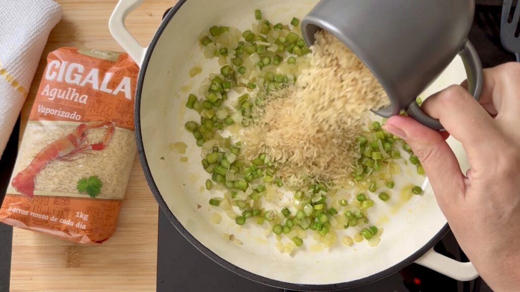 Junte o arroz ao refogado, tempere com sal e pimenta, e envolva bem para que os grãos fiquem bem cobertos com o refogado.